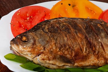 Kavrulmuş nehir balık sazan beyaz tabakta domates ile