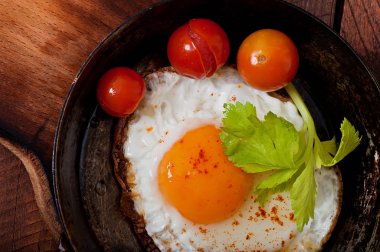 Bir tavada kızarmış yumurta ile acı biber serpilir.