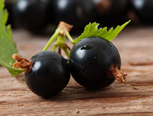 Black currant berries on an old wooden background. — Stock Photo, Image