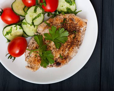 Kızarmış tavuk fileto dekore kiraz domates ve salatalık, üstten görünüm.