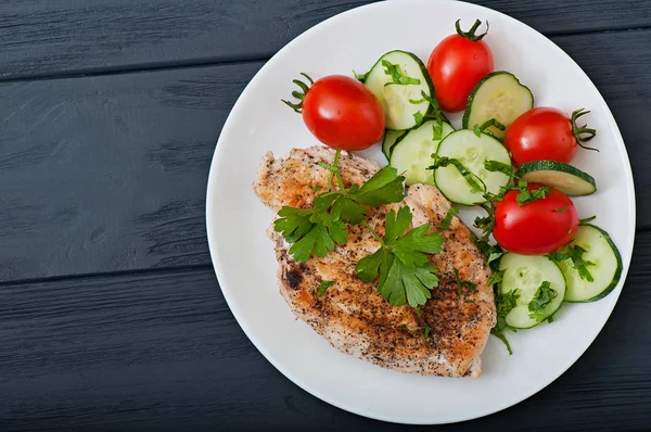 Kızarmış tavuk fileto dekore kiraz domates ve salatalık, üstten görünüm.