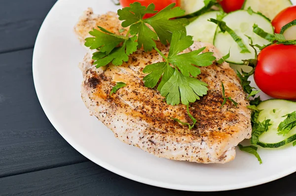Kiraz domates ve salatalık ile dekore edilmiş kızarmış tavuk fileto.