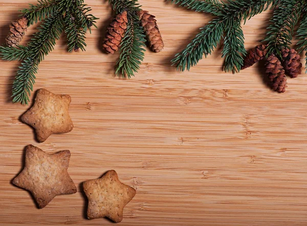 Komposition von Neujahrskeksen und Tannenzweigen auf einem hölzernen Hintergrund, Weihnachtshintergrund. Weihnachtsplätzchen. Stockbild