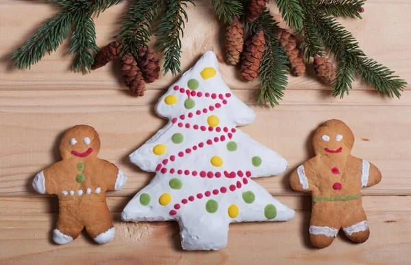 Komposition von Neujahrskeksen und Tannenzweigen auf einem hölzernen Hintergrund, Weihnachtshintergrund. Weihnachtsplätzchen. — Stockfoto