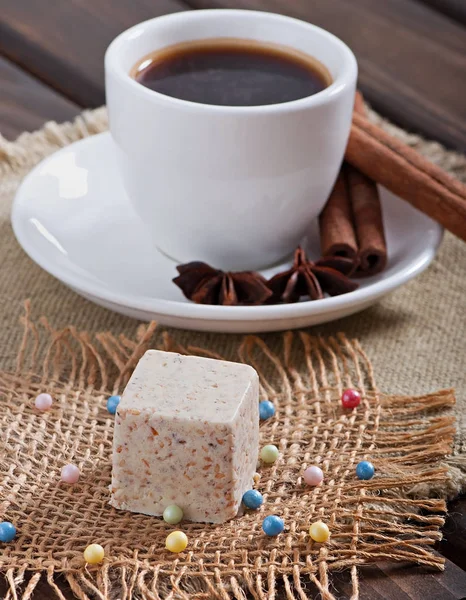 ごまのお菓子や古い木製の背景にスパイスと香り豊かなコーヒーをミルクします — ストック写真