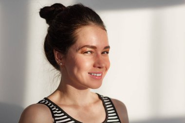 Genç ve çekici esmer kız beyaz bir duvarın yanında farklı duyguları, sert ışığı, ışığı ve gölgesi olan.