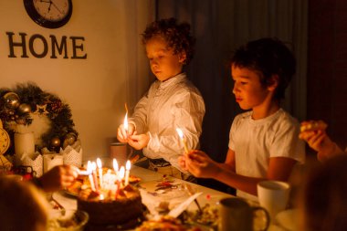 Çocuklar doğum günü pastasında mum yakıyor beyaz bir masa üstünde çocuklar beyaz bir masada doğum günü pastasının üzerinde mum yakıyor.