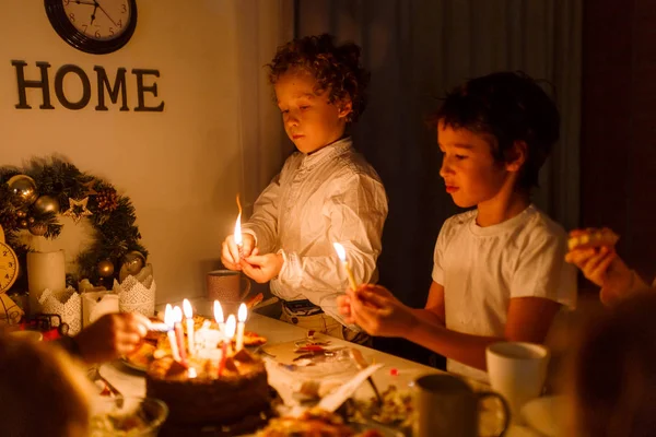 Çocuklar doğum günü pastasında mum yakıyor beyaz bir masa üstünde çocuklar beyaz bir masada doğum günü pastasının üzerinde mum yakıyor.