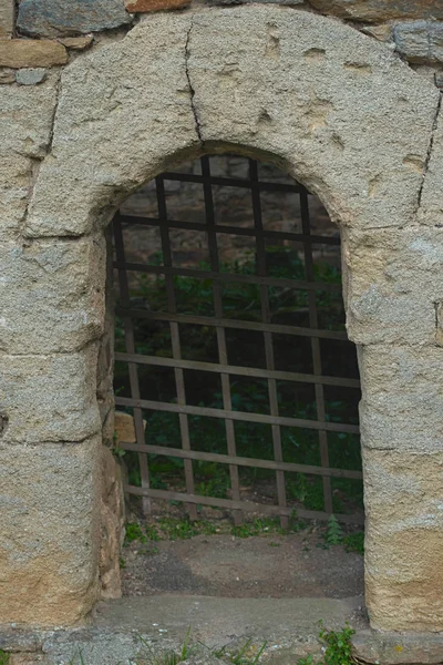 Arco de pedra e portão de metal rústico representando a entrada do calabouço — Fotografia de Stock
