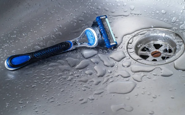 disposable razor on wet washbasin.closeup