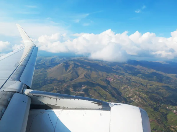 Крыло самолета на голубом небе, облака и горы — стоковое фото