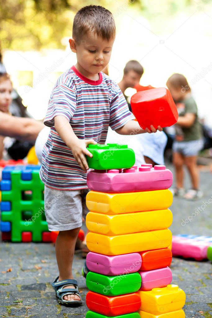Cute boy playing with buiding toy colorful blocks. Kid with happy face playing with plastic bricks. Plastic Large Toy.