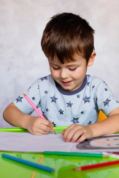 Liten pojke ritar med färgpennor. Grabben, ritar en bild för fädernas dag. Liten pojke ritar vid bordet. — Stockfoto