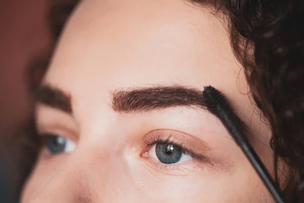 El trabajo de un maquillador profesional. Mujer joven sometida a un procedimiento de corrección de cejas. Rímel de cejas — Foto de Stock