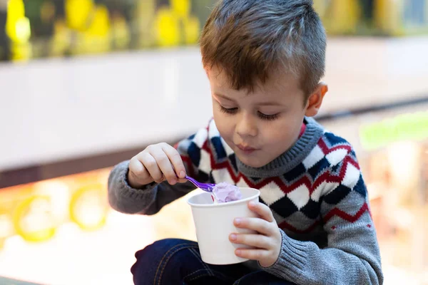 Chłopiec je smaczne lody. Kubek lodów w rękach chłopca. — Zdjęcie stockowe