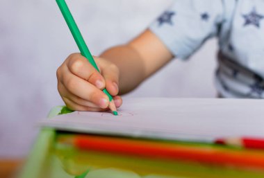 Çocukça el çizimlerine yakın çekim. Küçük çocuk renkli kalemler tutuyor. Babalar günü için resim çiziyorsun. Küçük çocuk masaya resim çizer..