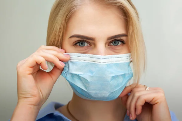 Tıbbi maskeli güzel kadın doktor. SARS-Cov-2 'ye karşı yüzünde cerrahi maske olan genç bir kadının yakın çekimi..