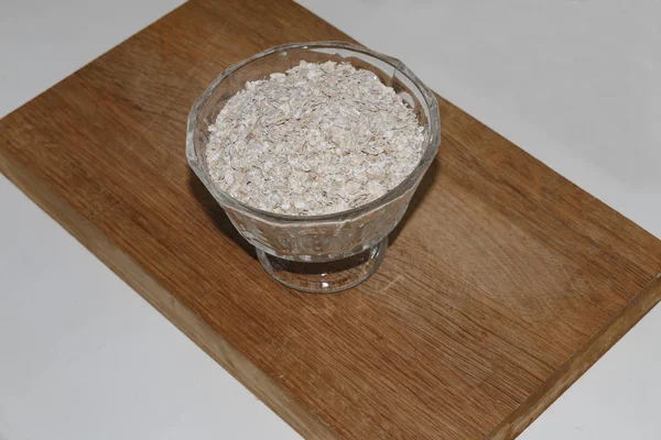 Oat flakes in a bowl on a wooden stand — Stock Photo, Image