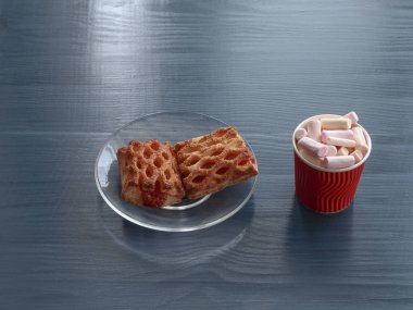 Reçel şeffaf cam levha ve ahşap bir masa üzerinde kırmızı kupada marshmallow ile ev yapımı kurabiye