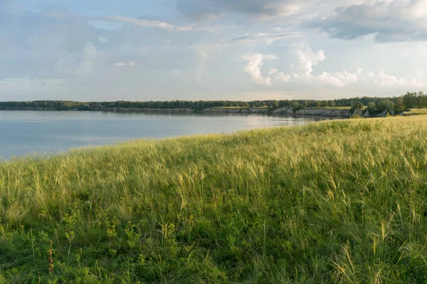 Bellissimo campo sulla riva del fiume sotto il cielo blu — Foto Stock