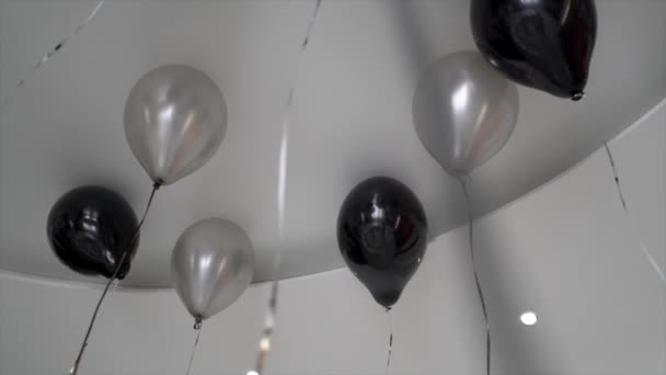 Black and white balloons fly under the ceiling — Stock Video