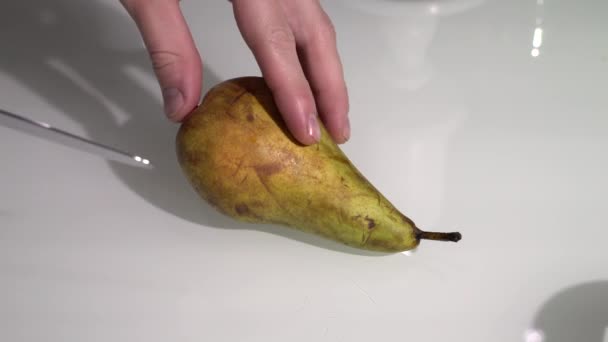 Отрезает кусок от спелой груши на столе — стоковое видео