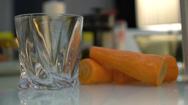 将鲜榨的果汁倒入玻璃杯中 一杯胡萝卜新鲜果汁和一桌胡萝卜 — 图库视频影像