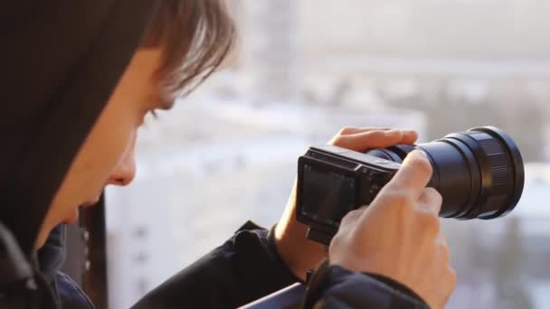 一个年轻人从窗口到照相机看城市 — 图库视频影像