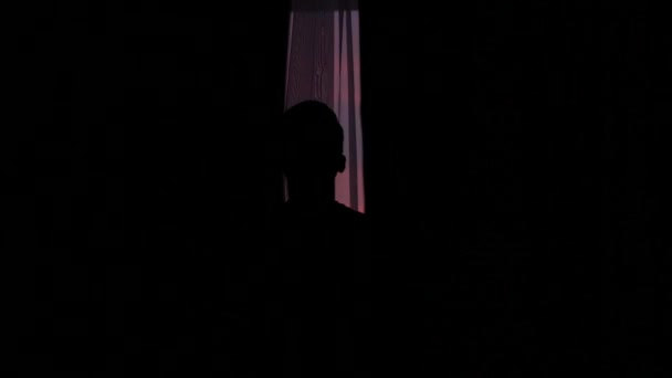 一个年轻男子的剪影打开窗帘对一个美丽的夕阳窗口 — 图库视频影像