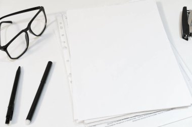 Beyaz Ofis Masası. Kağıt, kalem, Zımba, beyaz bir arka plan üzerinde gözlük