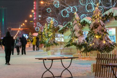 Noel dekorasyonu ve yürüyen insanları olan bir sokak. Akşam şehir caddesinde fuar