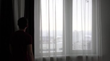 genç adam üstünde büyük pencere Perdeleri kapatır