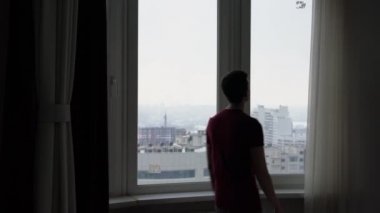 adam büyük pencerede tül Perdeleri kapatır
