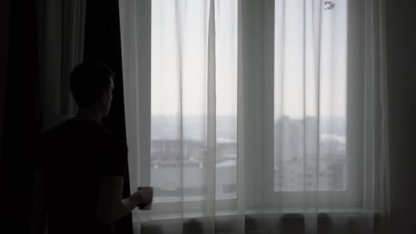 Young Man Looks Out Window City Drinks Tea — Stock Video