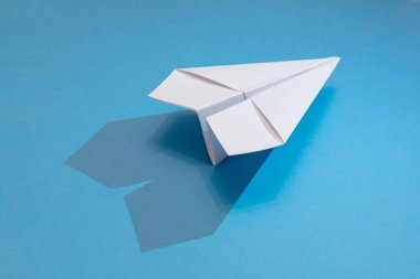 gölgeli mavi kağıt arka plan üzerinde beyaz kağıt uçak