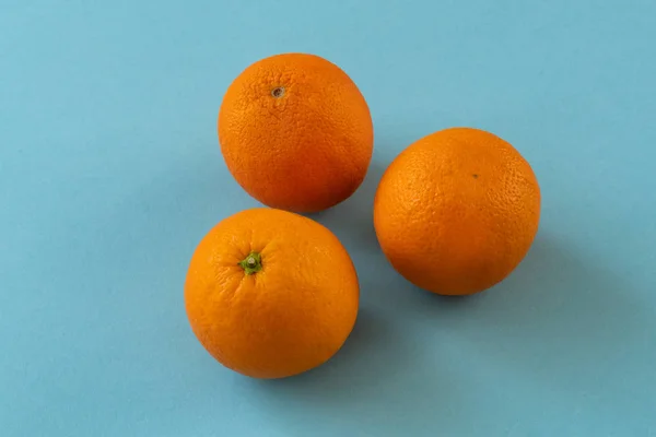 Drei Helle Orangen Auf Blauem Papierhintergrund Stockfoto