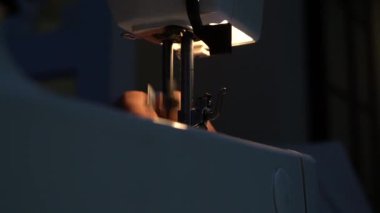 Geceleri dikiş makinesinin üzerinde diker mavi bir kumaş yakın plan.