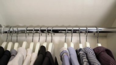 Bir adamın eli, dolaptaki askıdaki gömleği alır..