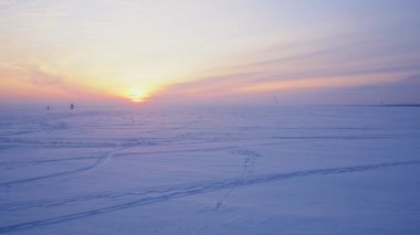 Donmuş gölün üzerinde güzel bir gün batımı ve karda kayak yapan uçurtmacılar..