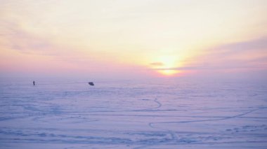 Karlı bir tarlada kar kaykaycısı güzel bir günbatımının arka planında.