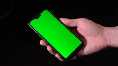 Günlük giysili bir adam oturur ve yerine yeşil ekran bir tablet kullanır..