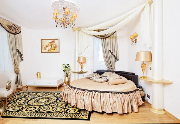 Golden classical bedroom interior with round bed and small table