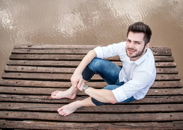 Ahşap güverte üzerinde oturan genç adam