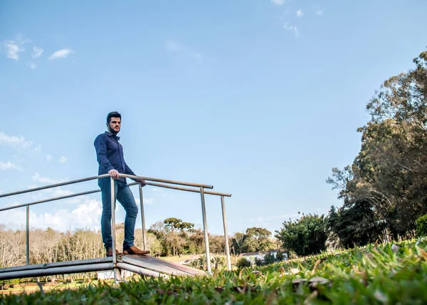 Rapaz parado sobre ponte contra o ceu azul