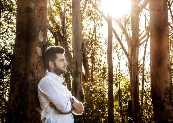 Rapaz com os braos cruzados em uma floresta