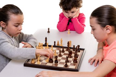 Kız kardeşler birlikte satranç oynuyorlar. Beyazlar üzerinde izole edilmiş. Çocuk konsantrasyonu kavramı.