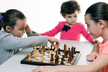 Kız kardeşler birlikte satranç oynuyorlar. Beyazlar üzerinde izole edilmiş. Çocuk konsantrasyonu kavramı.