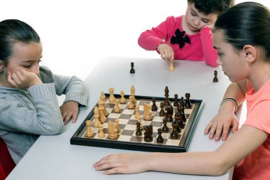 Kız kardeşler birlikte satranç oynuyorlar. Beyazlar üzerinde izole edilmiş. Çocuk konsantrasyonu kavramı.
