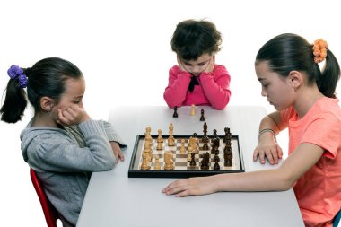 Kız kardeşler birlikte satranç oynuyorlar. Beyazlar üzerinde izole edilmiş. Çocuk konsantrasyonu kavramı.