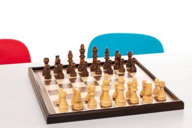 Satranç tahtası oyun için hazır. Arka planda çocuk sandalyeleri var..